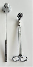 Load image into Gallery viewer, A set of candle snuffers and wick trimmers in various colors (black, rose gold, gold) positioned around a lit candle, with one snuffer interacting with the flame.